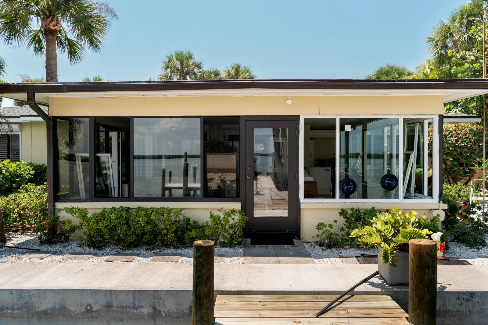 JMI glass-enclosure project with dark-framed windows and doors beside a landscaped Florida patio.