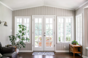 Elegant French doors with glass panes, opening to a scenic outdoor area from a cozy living room.