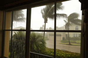 A home with hurricane impact windows protecting the interior during a tropical storm, with rain and wind visible outside.